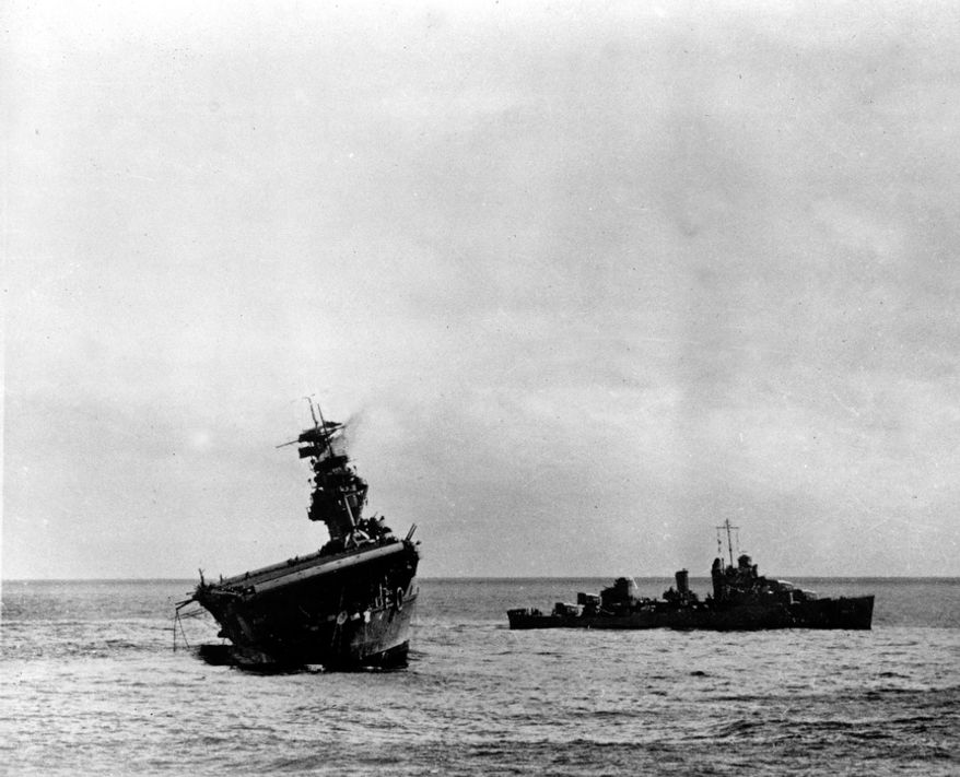 The USS Yorktown lists heavily to port after being struck by Japanese bombers and torpedo planes in the Battle of Midway on June 6, 1942, during World War II. A destroyer stands by at right to assist as a salvage crew on the flight deck tries to right the stricken aircraft carrier. A few hours later, the Yorktown was hit with Japanese torpedoes and sank. (Associated Press/U.S. Navy)