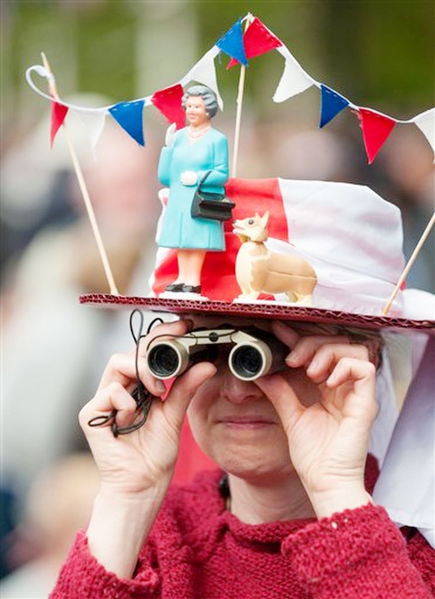 A woman in a fancy dress hat featuring Queen Elizabeth II and a corgi waits for the start of the Diamond Jubilee concert in London Monday June 4, 2012. But the queen's husband, Prince Philip, missed the concert after being hospitalized with a bladder infection. (AP Photo / Dominic Lipinski, Pool)