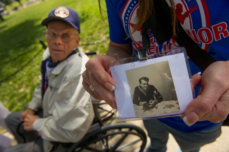 Retired World War II Navy veteran Jess Robertson, 88, of Springfield, Mo., looks at a photograph of himself when he was an active duty service member. Family members of Robertson say he was part of the Navy's Scouts and Raiders program which eventually became to be known as the Navy Seals. (Andrew Harnik/The Washington Times)