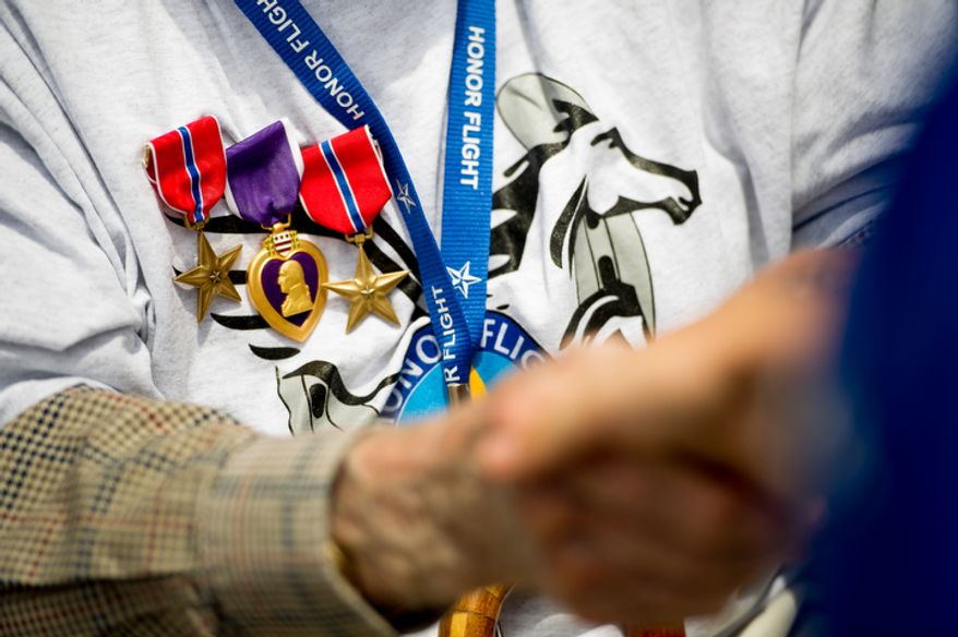 5th grader Olivia Szego, right, with Ashland Elementary School in Manassas, Va., shake hands with World War II veteran retired Army Pfc. Sheldon Franks, 93, of Corydon, Ind., who is the recipient of two bronze stars and a purple heart. (Andrew Harnik/The Washington Times)