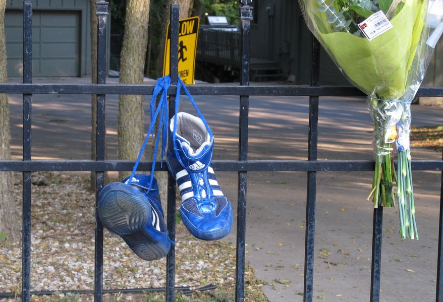 Wrestling shoes and flowers left by friends and neighbors hang June 7, 2012, from the fence of the home of Ron and Rebecca Bramlage and their four children in Junction City, Kan. The family died in a Florida plane crash, and three Bramlage boys were wrestlers. (Associated Press)