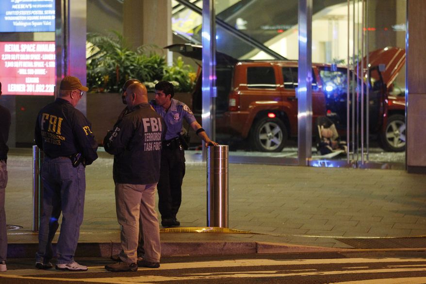 Members of the FBI Terrorism Task Force and police are on the scene after a sports utility vehicle crashed into an office building at 1050 Connecticut Avenue NW in Washington, Friday, June 8, 2012. According to news reports, police said the vehicle was intentionally driven into the building and the driver and the interior of the car was doused in gasoline.(AP Photo/Charles Dharapak)