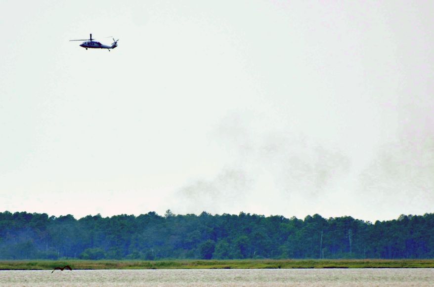 A military helicopter circles the area where an unmanned Navy aircraft crashed near Nanticoke, Md., on Monday, June 11, 2012. (AP Photo/The Daily Times, Steve Dickerson)