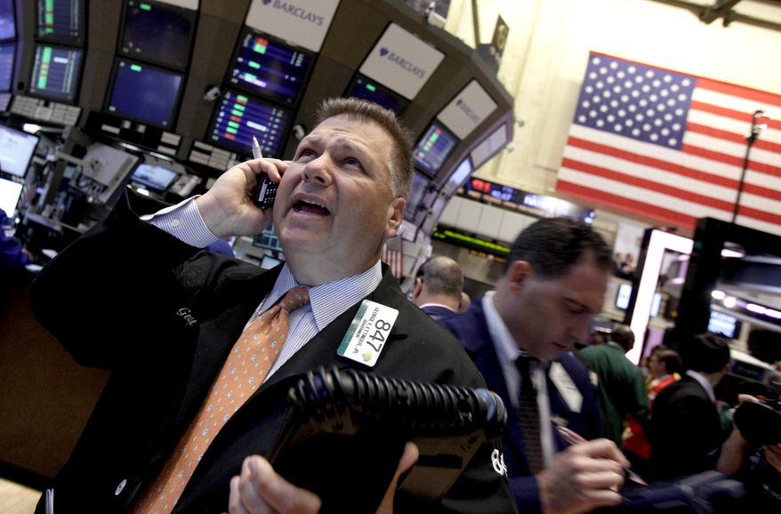 Trader George Ettinger (left) works June 11, 2012, on the floor of the New York Stock Exchange. (Associated Press)