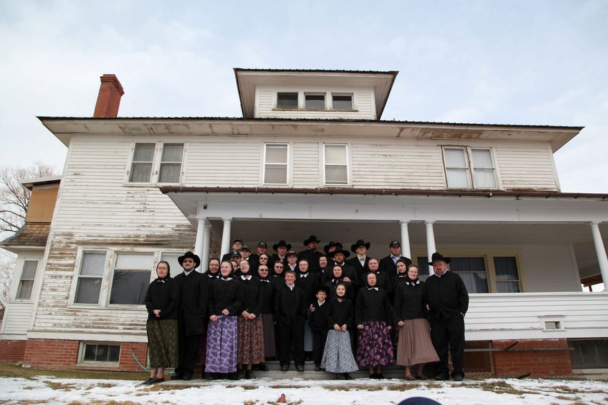 A Hutterite family is gathered in front of a house in Lewistown, Mont. "Meet the Hutterites" is a National Geographic documentary series about the small religious colony in rural Montana. Three Hutterite bishops have complained the series presents a "distorted" image of the sect. (National Geographic via Associated Press)