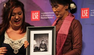 Myanmar opposition leader Aung San Suu Kyi (right) receives a picture of her father as a birthday gift after taking part in a round table at the London School of Economics and Political Science in London on Tuesday, June 19, 2012. (AP Photo/Elizabeth Dalziel)