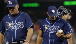 Tampa Bay Rays manager Joe Maddon, left, leads relief pitcher Joel Peralta from the baseball game during the eighth inning against the Washington Nationals at Nationals Park on Tuesday, June 19, 2012, in Washington. Peralta was ejected without throwing a pitch after the umpires found a foreign substance on his glove. The Rays won 5-4. (AP Photo/Alex Brandon)