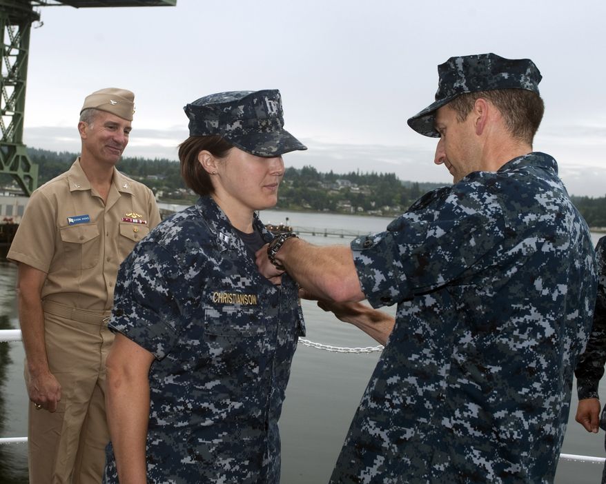 Lt. Britta Christianson, Gold Crew supply officer for the guided-missile submarine USS Ohio (SSGN 726), is presented with her Submarine Supply Corps "dolphins" by her commanding officer, Capt. Rodney Mills, during a ceremony at Puget Sound Naval Shipyard on June 22. Capt. Dixon Hicks, Ohio's former commanding officer, looks on. Christianson is the first female Supply Corps officer to qualify in submarines. (U.S. Navy photo by Chris Calnan/Released)