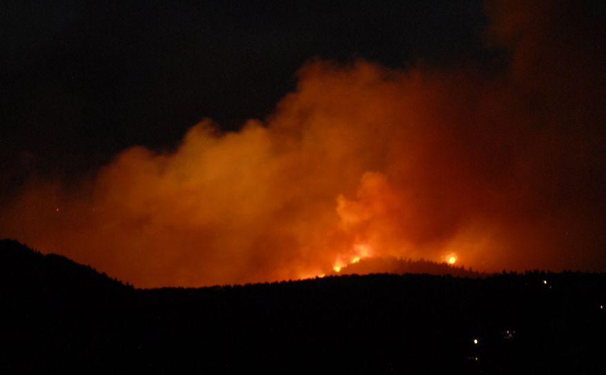 The evening sky glows orange with smoke and flames as the Waldo Canyon Fire rages west of the Garden of the Gods near Colorado Springs, Colo., on Saturday, June 23, 2012. ( AP Photo/Bryan Oller)