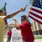 Andy Hernandez, carrying a Mexican flag (left), and Allison Culver, carrying an American flag, argue over Arizona&#39;s immigration law outside the State Capitol Building in Phoenix, Ariz. While finding much of the Arizona law unconstitutional, the U.S. Supreme Court said Monday that one part would stand — the portion requiring police to check the status of someone they suspect is not in the United States legally. (Arizona Republic via Associated Press)