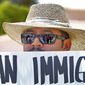 Gonzalo Hernandez stands outside a Scottsdale, Ariz., resort Monday protesting GOP presidential hopeful Mitt Romney, who was speaking inside, and Arizona&#39;s immigration law, a key part of which was upheld by the Supreme Court. (Associated Press)