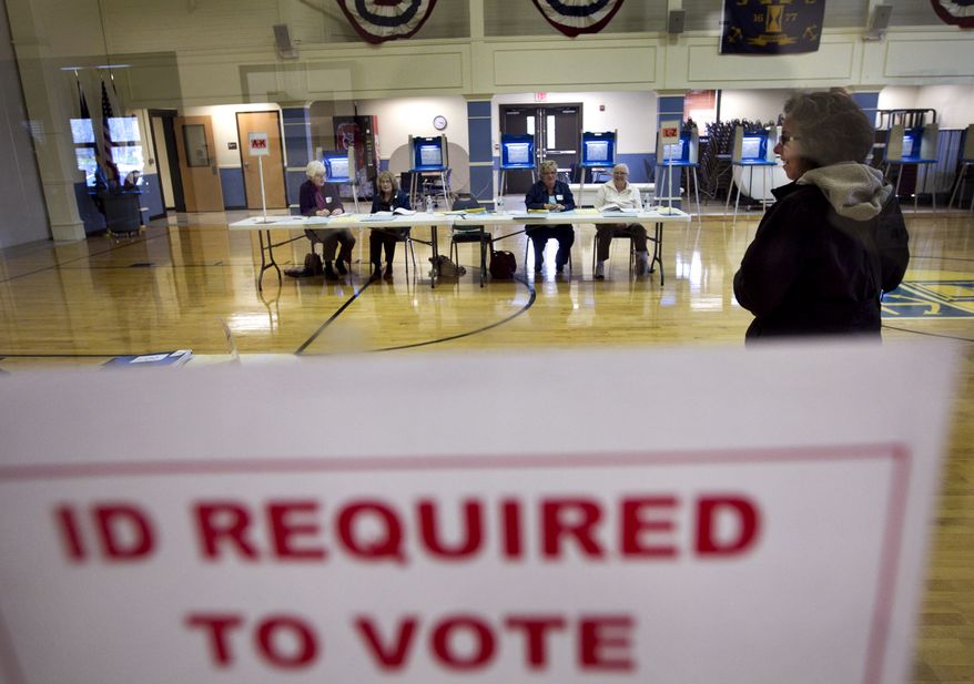 **FILE** A sign posted at the entrance of a polling station in East Greenwich, R.I., on April 24, 2012, advises voters that identification is required. (Associated Press)