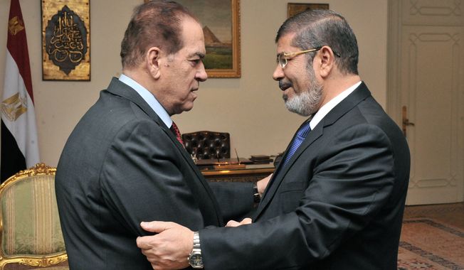 Kamal el-Ganzouri (left), Egypt&#x27;s caretaker prime minister, shakes hands with Egyptian President-elect Mohammed Morsi in Cairo on Monday, June 25, 2012. (AP Photo/Middle East News Agency)

