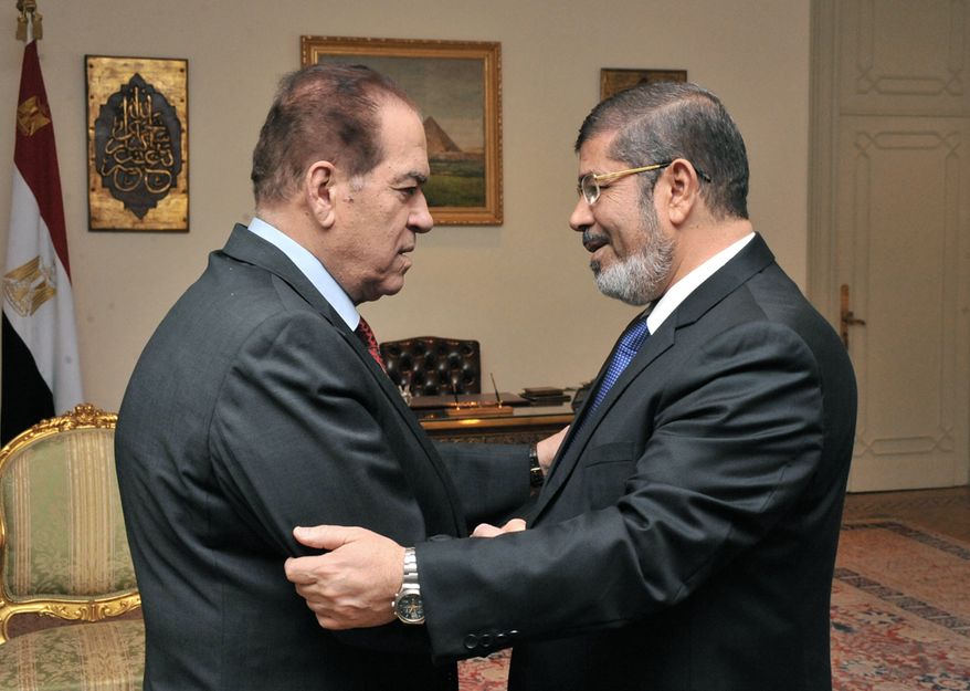 Kamal el-Ganzouri (left), Egypt's caretaker prime minister, shakes hands with Egyptian President-elect Mohammed Morsi in Cairo on Monday, June 25, 2012. (AP Photo/Middle East News Agency)