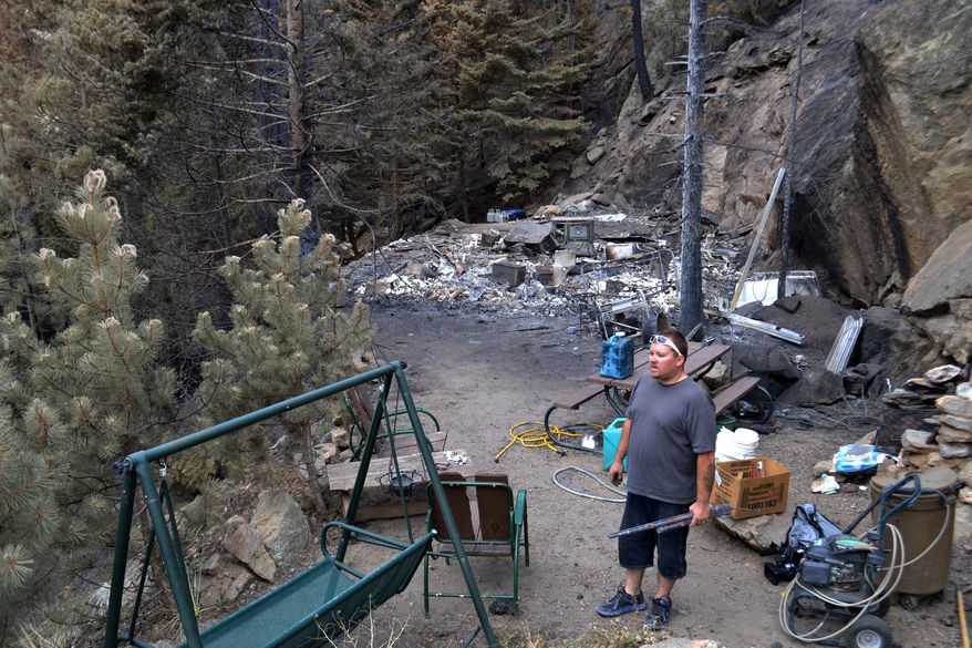 Jeff Corum Jr. stands in the charred ruins of his father's house on Kings Canyon Road in Bellvue, Colo., on Monday, June 25, 2012, after authorities allowed residents to return home. The Corum home was destroyed in the High Park wildfire, burning near Fort Collins. (AP Photo/P. Solomon Banda)