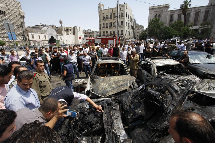 Syrians inspect burned cars June 28, 2012, at the site of a blast in the Syrian capital of Damascus. A strong explosion rocked the city near a busy market and the Palace of Justice, sending black smoke billowing into the sky. (Associated Press)