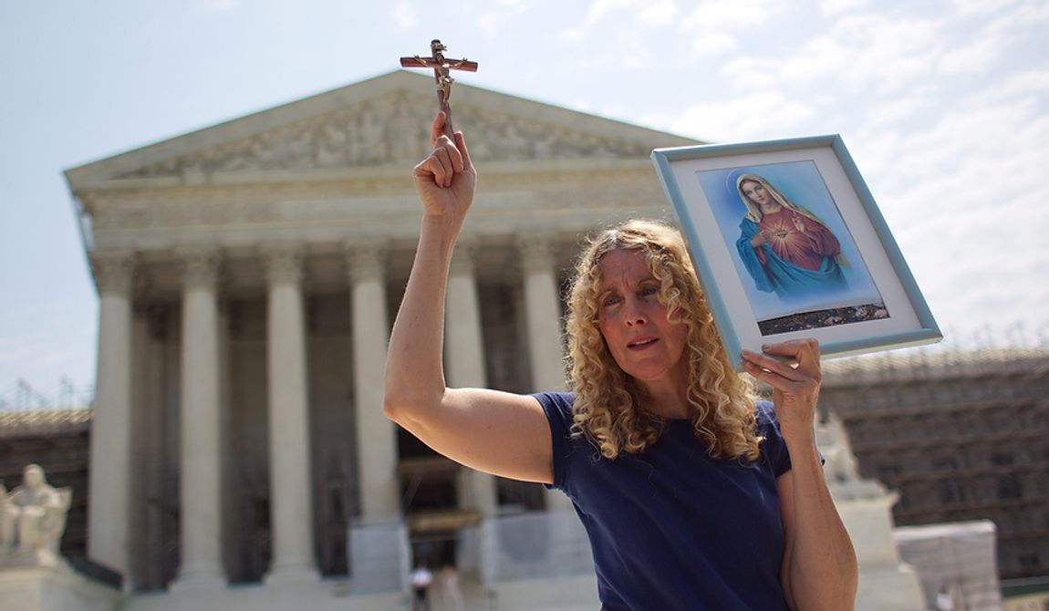 Carol Anderson of Williamsburg, Va., holds a cross outside the Supreme Court in Washington, Thursday, June 28, 2012, after the court&#x27;s ruling on health care.  (AP Photo/Evan Vucci)