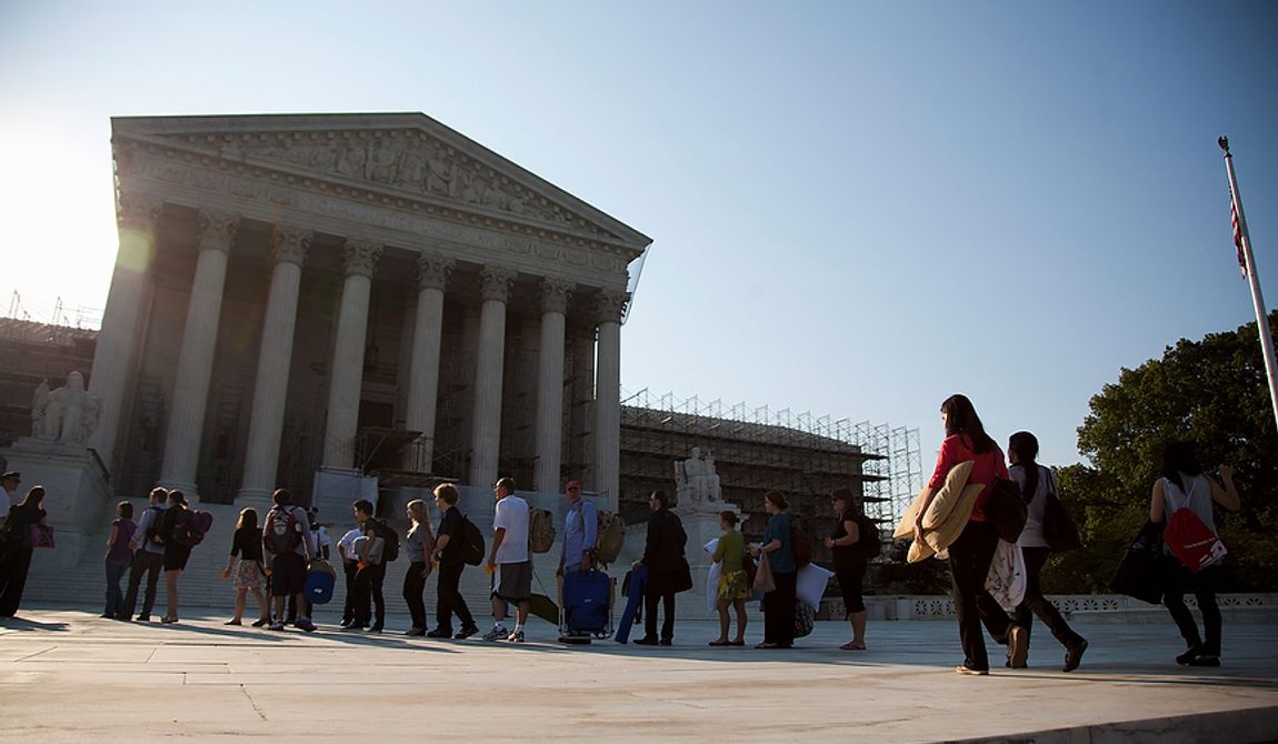 People who waited in line overnight to hear the Supreme Court on a landmark case on health care hold their belongings as they make their way into the court in Washington, Thursday, June 28, 2012.  (AP Photo/Evan Vucci)
