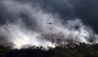 **FILE** A helicopters flies over as the Waldo Canyon fire continues to burn June 27, 2012, in Colorado Springs, Colo. (Associated Press)
