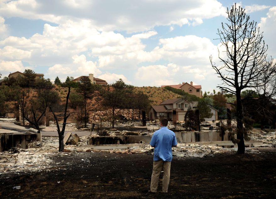 A secret service agent looks over the burnt homes in the Mountain Shadows neighborhood damaged by the Waldo Canyon Fire in Colorado Springs, Colo., Friday, June 29, 2012. After declaring a "major disaster" in the state early Friday and promising federal aid, President Barack Obama got a firsthand view of the wildfires and their toll on residential communities. More than 30,000 people have been evacuated in what is now the most destructive wildfire in state history. (AP Photo/The Denver Post, Joe Amon)