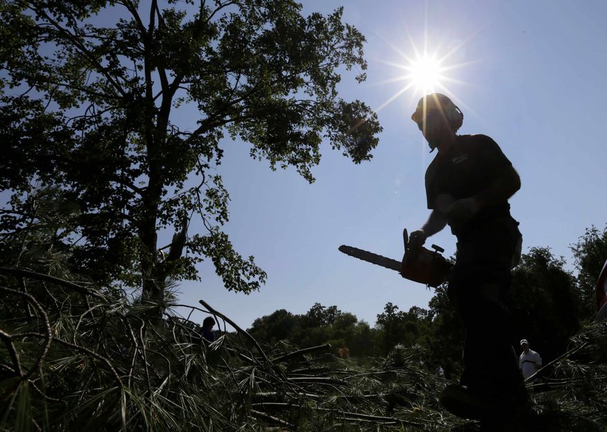 A worker uses a chainsaw to clear branches from a tree that fell onto the 14th fairway at Congressional Country Club in Bethesda, Md., Saturday, June 30, 2012, after a strong storm blew through overnight. The AT&T National golf tournament was postponed to allow workers to clear the course. (AP Photo/Patrick Semansky)
