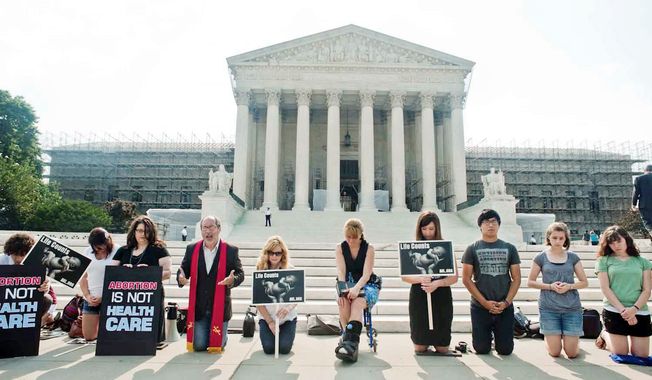 Members of Students For Life of America pray at the Supreme Court last week while waiting for a ruling on the health care reform law. The law was upheld last Thursday, and foes&#x27; attention now turns to the presidential election in November, which holds the key to the law&#x27;s fate. (Raymond Thompson Jr./The Washington Times) ** FILE **