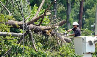 A utility worker clears a downed tree in Springfield, Va., Sunday, July 1, 2012. A severe storm late Friday knocked out power to approximately one million residents, traffic signals and businesses in the  region.  (AP Photo/Cliff Owen)