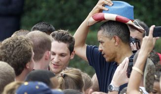 President Obama puts on a red, white, and blue hat, while visiting with service members during the Independence Day celebration on the from the South Lawn of the White House, Wednesday, July 4, 2012. (AP Photo/Haraz N. Ghanbari)
