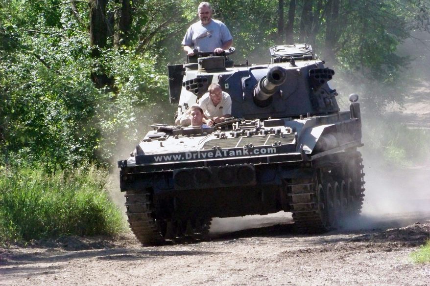Nick Walker takes the controls while his father, Brad, looks out from the turret. 'Drive-a-Tank' owner Tony Borglum goes along for the ride. (Associated Press)