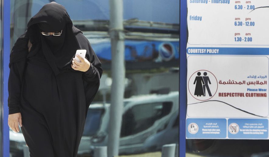 ** FILE ** In this photo taken Monday, June 25, 2012, a muslim Emirati woman passes by a dress code sign at a shopping mall in Dubai, United Arab Emirates. (AP Photo/Kamran Jebreili)