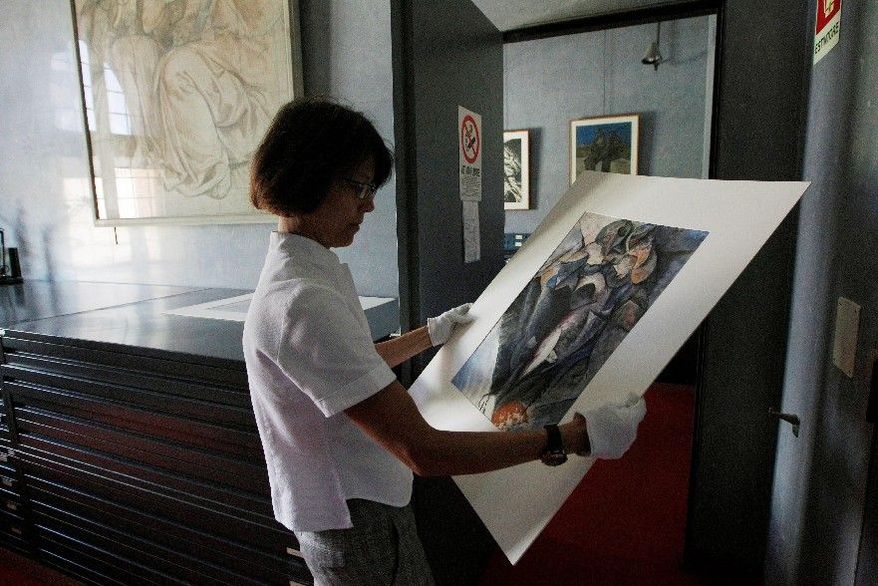 Francesca Rossi, curator in charge of the Sforzesco Castle drawings collection, examines a work by Umberto Boccioni in the same room where Simone Peterzano sketches are preserved. She says art historians who claim to have found early drawings of Caravaggio, a student of Peterzano, are naive and "never came here in the drawings department to scrutinize the works." Yet Maurizio Bernardelli Curuz says he was able to visit the collection after hours and "saw the originals." (Associated Press)