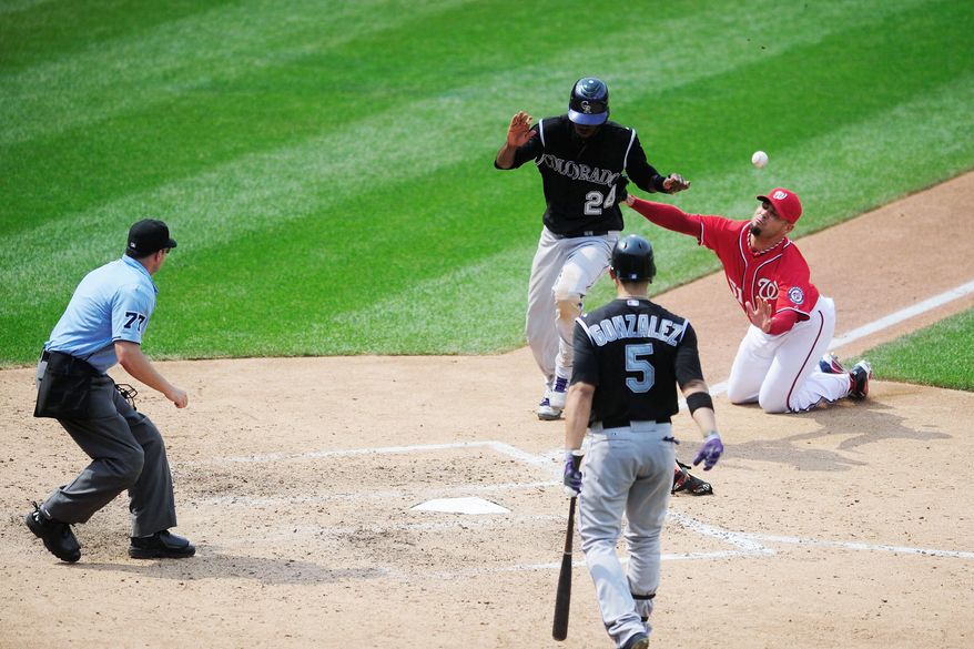 Dexter Fowler scores on a wild pitch by Washington reliever Michael Gonzalez (right) to tie the game 3-3 in the eighth inning. Colorado won 4-3 to take two of three games in the weeked series at Nationals Park. (Ryan M.L. Young/The Washington Times)