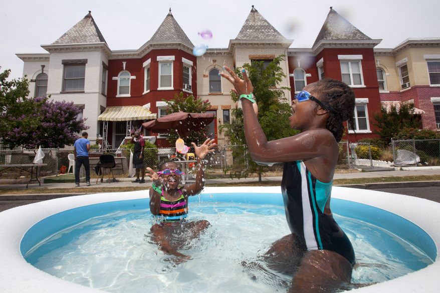 Nia Bailey (left), 8, of Washington, and Amari Swint, 8, of Philadelphia, throw water balloons while in an inflatable pool July 7, 2012, during a block party northwest Washington, D.C., during record heat with temperatures in the triple digits. (Associated Press)