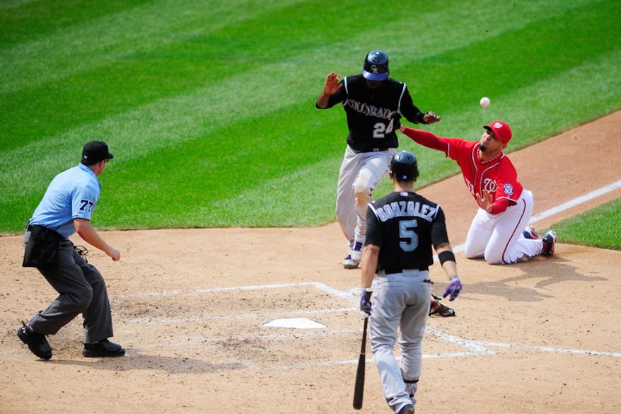 Dexter Fowler (24) comes across home plate as the Nationals' Michael Gonzalez (51) attempts to cover the plate after throwing a wild pitch to Carlos Gonzalez (6) at Nationals Park. The run tied the game at 3-3 and the Rockies would eventually win 4-3. (Ryan M.L. Young/The Washington Times)