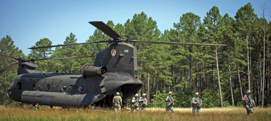 A portion of the sapper platoon makes their way through tall grass after arriving on a Chinook helicopter en route to a base for the next training mission. For 10 days and nine nights during the second phase of the 28-day sapper course, the soldiers persevered with only a couple of hours of sleep each night and one or two packaged meals a day. (Rod Lamkey Jr./The Washington Times)