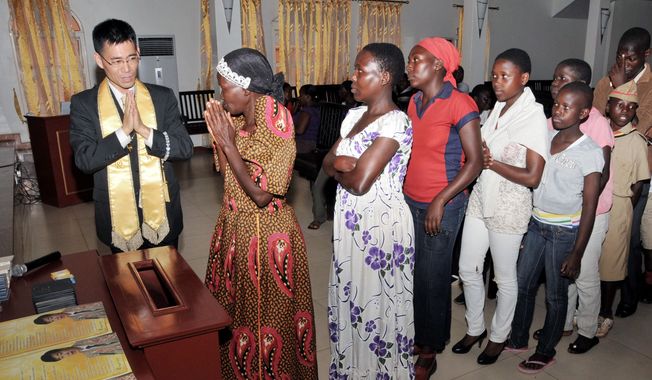 Happy Science Pastor Tomohiko Nakagawa (left), leads prayers with the faithful in Kampala, Uganda. The religion, with origins in Japan, is quickly amassing a following in Uganda with a campaign that has attracted the attention of Christian clerics offended by its beliefs. (Associated Press)