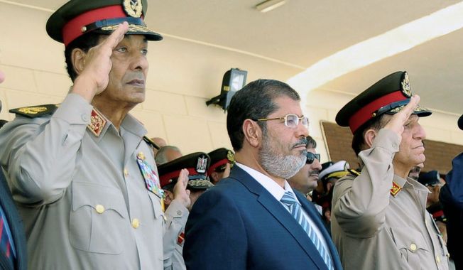 Egyptian President Mohammed Morsi (center) is flanked by Field Marshal Hussein Tantawi (left) and Chief of Staff Sami Anan at a ceremony at an Air Force base in Cairo on Tuesday. U.S. Secretary of State Hillary Rodham Clinton arrives in the Egyptian capital on Saturday amid growing concern in Washington that a power struggle in Egypt could imperil the transition to democratic rule. (Associated Press)