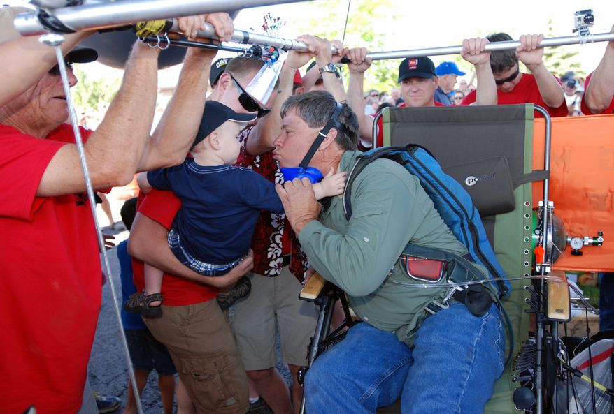 Lawn chair balloonist Kent Couch leans in for a kiss from a grandson before taking flight from his gas station with Iraqi adventurer Fareed Lafta on Saturday, July 14, 2012 in Bend, Ore. (AP Photo/Jeff Barnard)