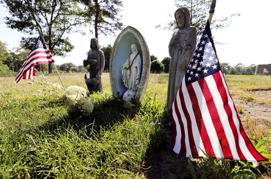 Religious statues and American flags mark the grave to which Mary Richardson Kennedy's body was moved in St. Francis Xavier Cemetery in Centerville, Mass. (AP Photo/Michael Dwyer)
