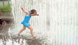 Annabel Helms, 4, from the District, cools off in the water fountain at The Yards Park on Monday. The area is experiencing another surge of steamy weather. (Raymond Thompson/The Washington Times)