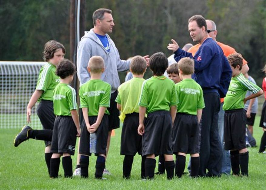 This Oct. 1, 2011 photo shows coaches Jeff Goldman, left, and Jack Russell with their team, the Sounders, at the Raynham Soccer complex in Raynham, Mass. Both Goldman and Russell have sons on the team. Parents who sign up to coach appreciate the experience because it's usually fun and builds dedicated time with their kids into their schedule. Often, they're also trying to ensure that their kids learn proper techniques and good sportsmanship. (AP Photo/Carolyn Lessard)
