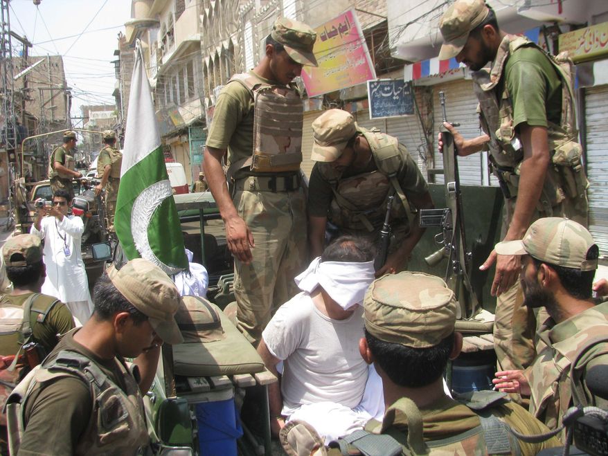 Pakistani soldiers escort an alleged suspect arrested during a crackdown operation against militants in Bannu, Pakistan, on Monday, July 16, 2012. (AP Photo/Ijaz Mohammed)