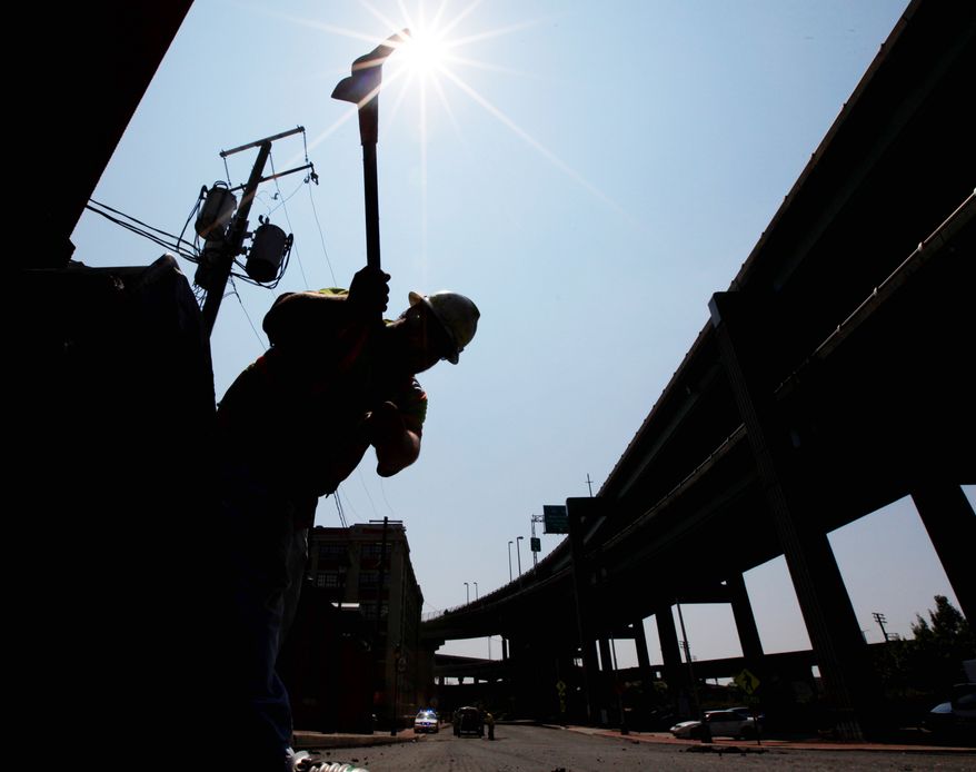 Michael Webb of Dominion Paving endures the heat as he uses a pickax while working on a road project near downtown Richmond on Tuesday. (Associated Press)