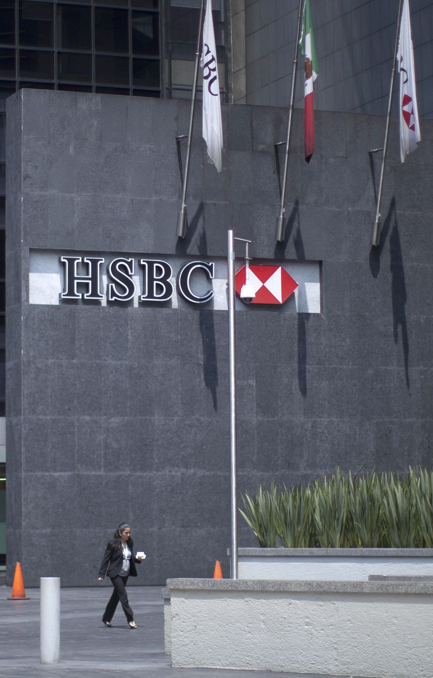 A woman walks in front of the HSBC bank headquarters in Mexico City, Tuesday, July 17, 2012. The chief compliance officer of Britain's HSBC Tuesday said he was stepping down from that position after an investigation found that lax controls at the international bank allowed Mexican drug cartels to launder billions of dollars through its U.S. operation and other illicit transactions. (AP Photo/Alexandre Meneghini)