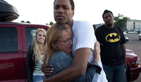 Judy Goos hugs her daughter&#39;s friend, Isaiah Bow, 20, while eyewitnesses Emma Goos (left), 19, and Terrell Wallin, 20, gather July 20, 2012, outside Gateway High School in Aurora, Colo., where witnesses were brought for questioning after a gunman fired into a crowded movie theater, killing at least 12 people and injuring at least 50 others. (Associated Press)