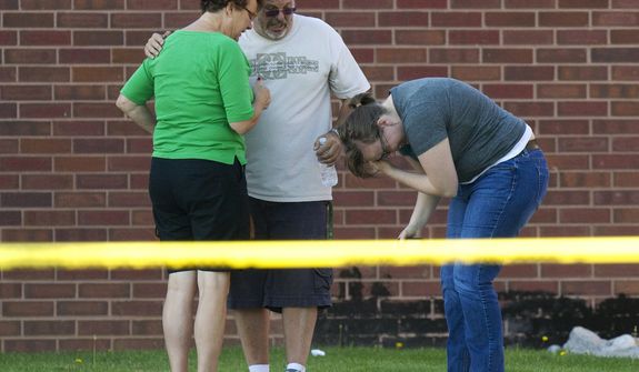 Tom Sullivan (center) stands with family members July 20, 2012, outside Gateway High School in Aurora, Colo., where witness were brought for questioning after a gunman opened fire in a crowded movie theater, killing 12 people and injuring at least 50 others. (Associated Press)