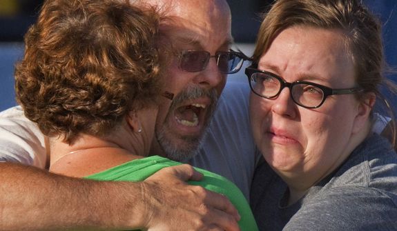Tom Sullivan (center) embraces family members July 20, 2012, outside Gateway High School in Aurora, Colo., where witness were brought for questioning after a gunman opened fire in a crowded movie theater, killing 12 people and injuring at least 50 others. Sullivan was frantically searching for his son, Alex, who was celebrating his 27th birthday by going to see &quot;The Dark Knight Rises,&quot; the movie where the gunman opened fire. (Associated Press)