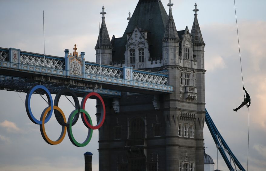 British Royal Marine Martyn Williams, right, rappels down from a Royal Navy Sea King helicopter into the Tower of London with the Olympic torch, Friday, July 20, 2012, in London. The Olympic Torch arrived in London after it was carried around England in a relay of torchbearers to make its way to the London 2012 Olympic Games opening ceremony on July 27, 2012. (AP Photo/Jae C. Hong)