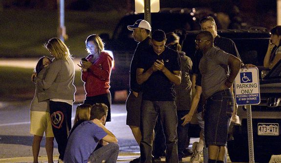 People use mobile devices July 20, 2012, as they wait outside Gateway High School in Aurora, Colo., where witness were brought for questioning after a gunman opened fire in a crowded movie theater, killing 12 people and injuring at least 50 others. (Associated Press)