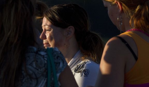 A woman cries July 20, 2012, outside Gateway High School in Aurora, Colo., where witness were brought for questioning after a gunman opened fire in a crowded movie theater, killing 12 people and injuring at least 50 others. (Associated Press)